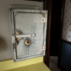 Drewniana szafka na licznik elektryczny, stylizowana na rustykalną, z widocznym zamkiem i zawiasami.