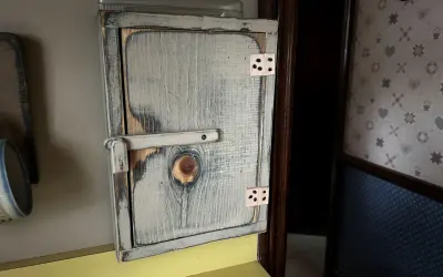 Drewniana szafka na licznik elektryczny, stylizowana na rustykalną, z widocznym zamkiem i zawiasami.